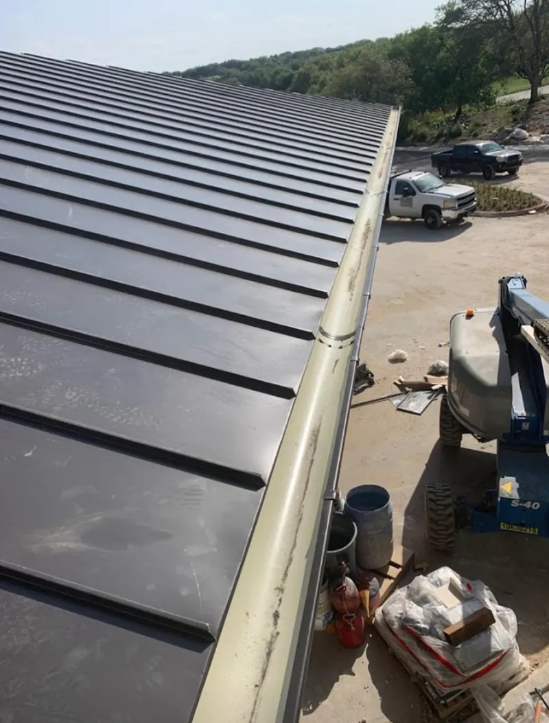 Standing seam panel and gutter detail on a metal roofing jobsite in Bondurant